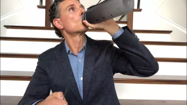 man in suit drinking from a tumbler water bottle