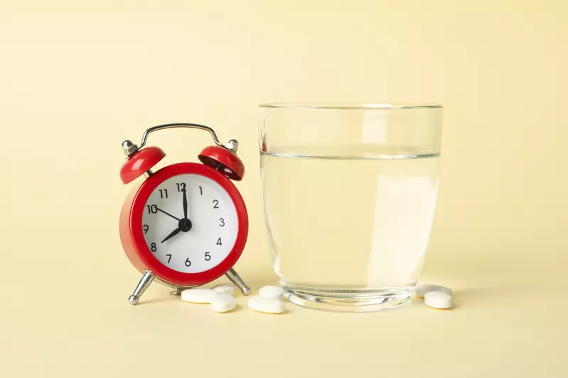 Photo of a clock with medicine and a glass of water