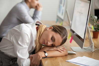 woman sleeping at work with her head on the desk